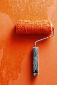 Orange Paint Roller On Freshly Painted Wall